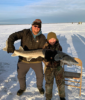 Another father and son team display their massive sturgeon catch on Black Lake.