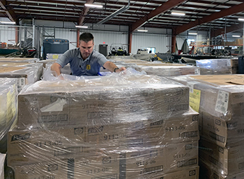 A conservation officer is shown in a storehouse with coronavirus pandemic supplies being shipped to DNR offices.