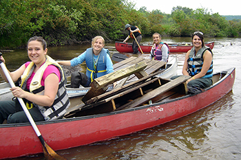 Volunteers are shown in a canoe with garbage they hauled out of the Boardman River.