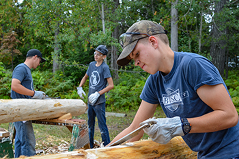 Three young men work on a volunteer maintenance project at Fort Wilkins Historic State Park.