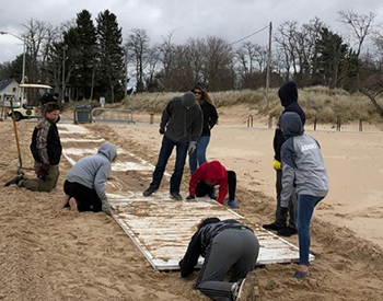 volunteers work on boardwalk over sand