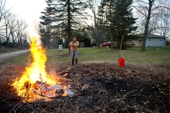 A man demonstrates the correct way to burn debris outside. 