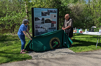 An interpretive sign along the Mike Levine Lakelands Trail is shown being revealed to the public.