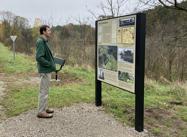 A DNR staffer stops to read an interpretive sign along the Mike Levine Lakelands Trail.