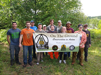 Group of volunteers holding On the Ground banner