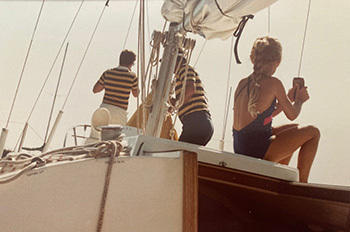 older photo of people sitting on sailboat