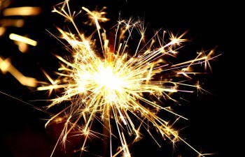 A close-up of a lit sparkler at night.