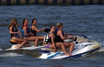 A group of young women with pale skin riding two sea-doos.