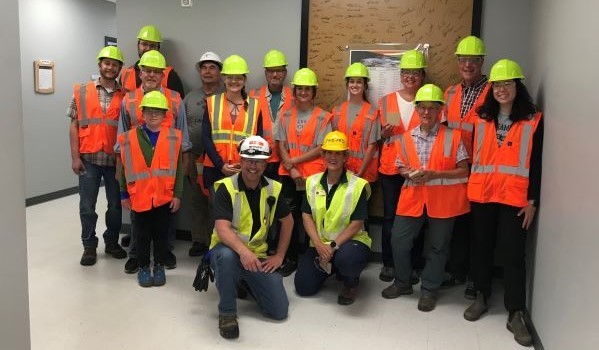 A group of landowners wearing safety gear smile for a photo at the Arauco facility