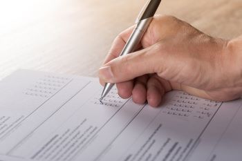 Image of a person using a pen to fill out a survey