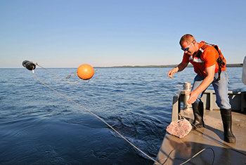 researcher deploys receiver off boat into water