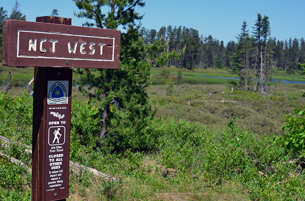 A trail sign for the North Country Trail is shown on a sunny day in Baraga County.