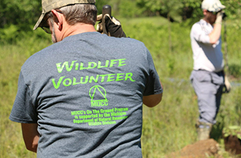 man holding shovel wearing shirt that says Wildlife Volunteer on the back