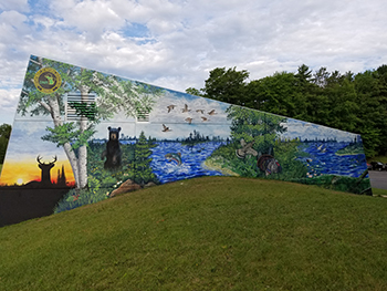 A wide shot shows the entire mural at the DNR Customer Service Center in Escanaba.