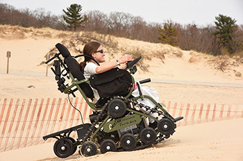 woman riding in track chair on beach