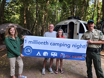 campers holding 1 millionth camping night sign in campsite