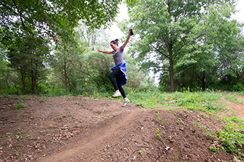 woman jumping up on trail