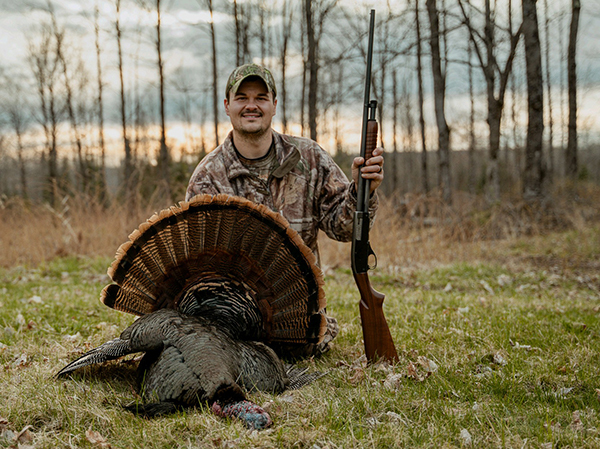 Ryan McGillviray is pictured with his firearm and a turkey he bagged.