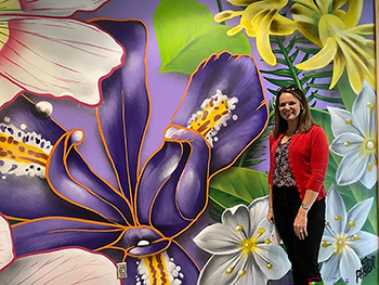 Woman standing in front of mural featuring colorful Michigan wildflowers