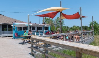 Visitors sit under umbrellas eating ice cream next to a bright blue concession stand.