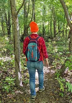 hiker with blaze orange hat on trail