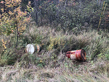 Two barrels, one green and one reddish-orange, dumped into a ditch in Marquette County.