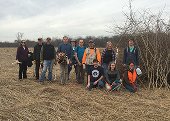 group of volunteers next to brush pile in field