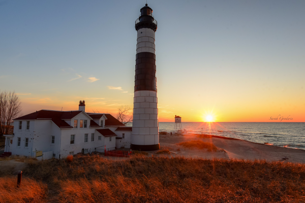 A crimson sunset shines fading, red light across the Big Sable lighthouse.