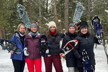 woman in a group holding up snowshoes