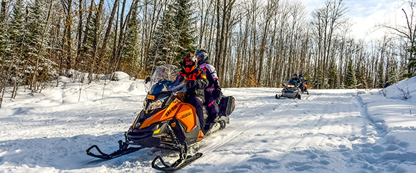 three snowmobiles on snowy trail