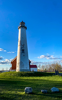 The lighthouse is shown on a clear day, with blue skies above.