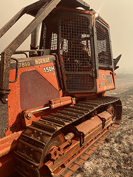 A bulldozer operator is shown using his equipment in Texas to fight fire.