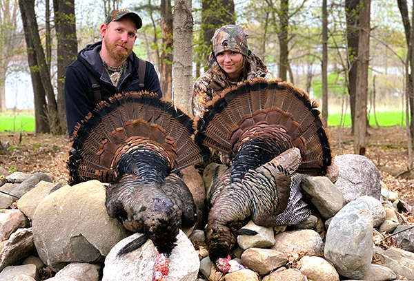 two hunters with harvested wild turkeys