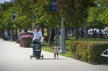 A woman and child are shown walking along a Detroit River pathway.