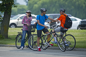 family stopped on bikes, with cars parked in background