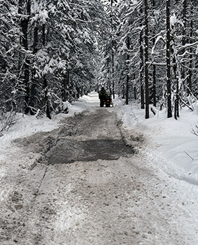 A rider stops a snowmobile after a water hole across a snowmobile trail.