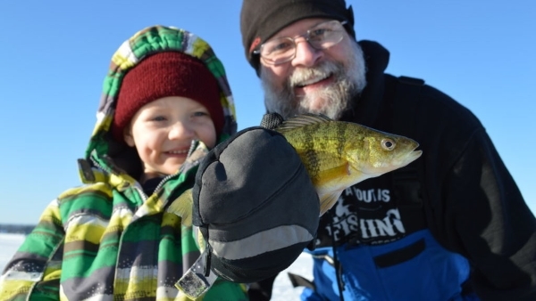 young, smiling boy holding fish and smiling man