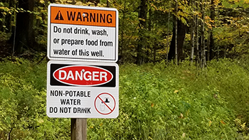 A sign posted warning the public not to drink the water is shown.