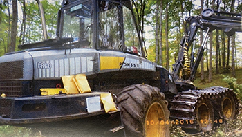 A trail camera image shows a machine used to illegally cut timber in Dickinson County.