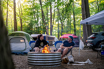 two campers sitting in campsite by fire