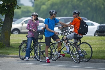 Three people, presumably a family, take a moment to rest and laugh with each other while on their bikes.