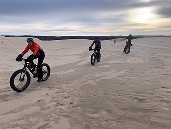 Three fat-tire bikers are shown riding the beach at Silver Lake.