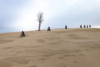 Fat-tire bikers roll over one of the dunes at Silver Lake.