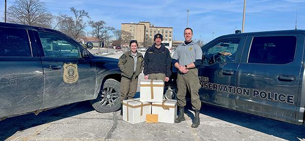 conservation officers with trucks and boxes of game meat to donate