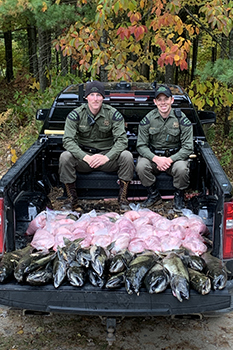 Two conservation officers in truck bed full of illegally taken salmon to donate