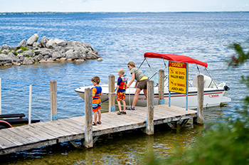 two kids and adult loading boat at boating access site