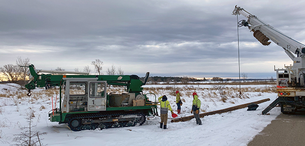 A work prepares to erect an osprey nest platform on a frozen, snow-covered marsh.