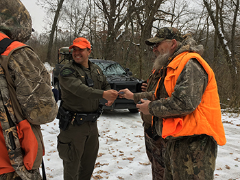 co checking deer license in group of hunters