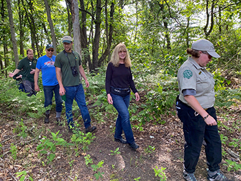 Men and women are shown walking in a forest at the state game area.