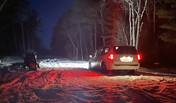 A white minivan stuck in the snow along Luce County Road 407 is shown.